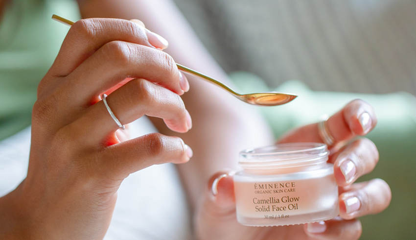 Woman holding jar of Camellia Glow Solid Facial Oil with a spoon